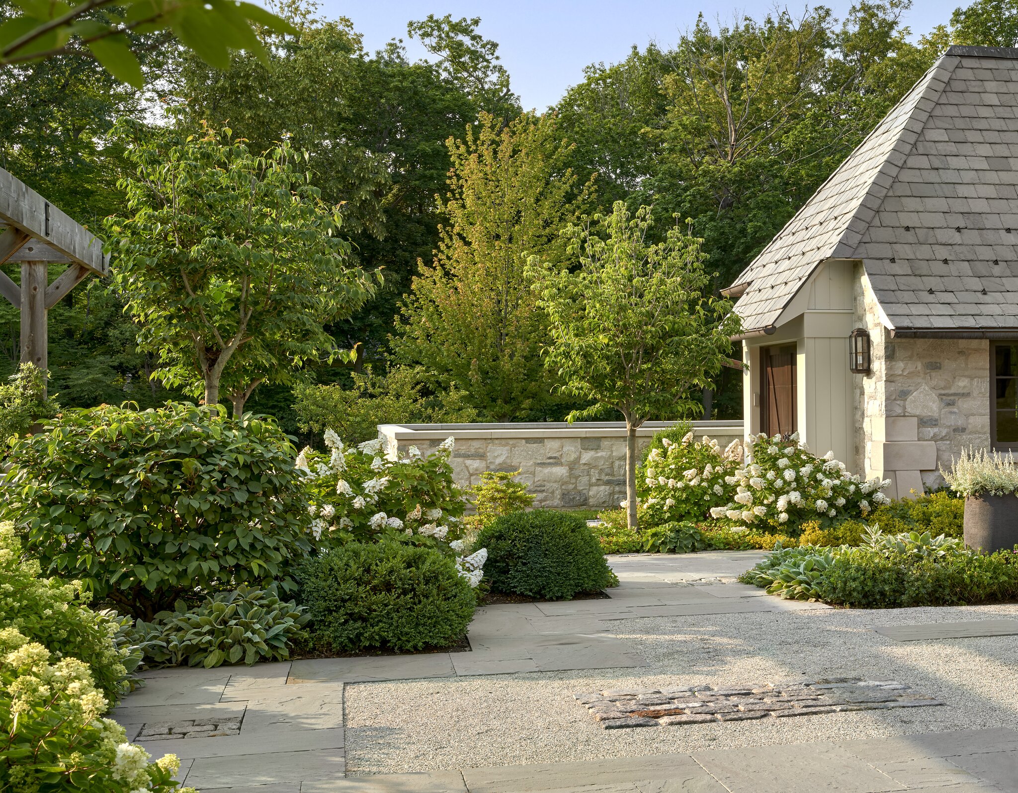 Charming garden with stone house and lush greenery.