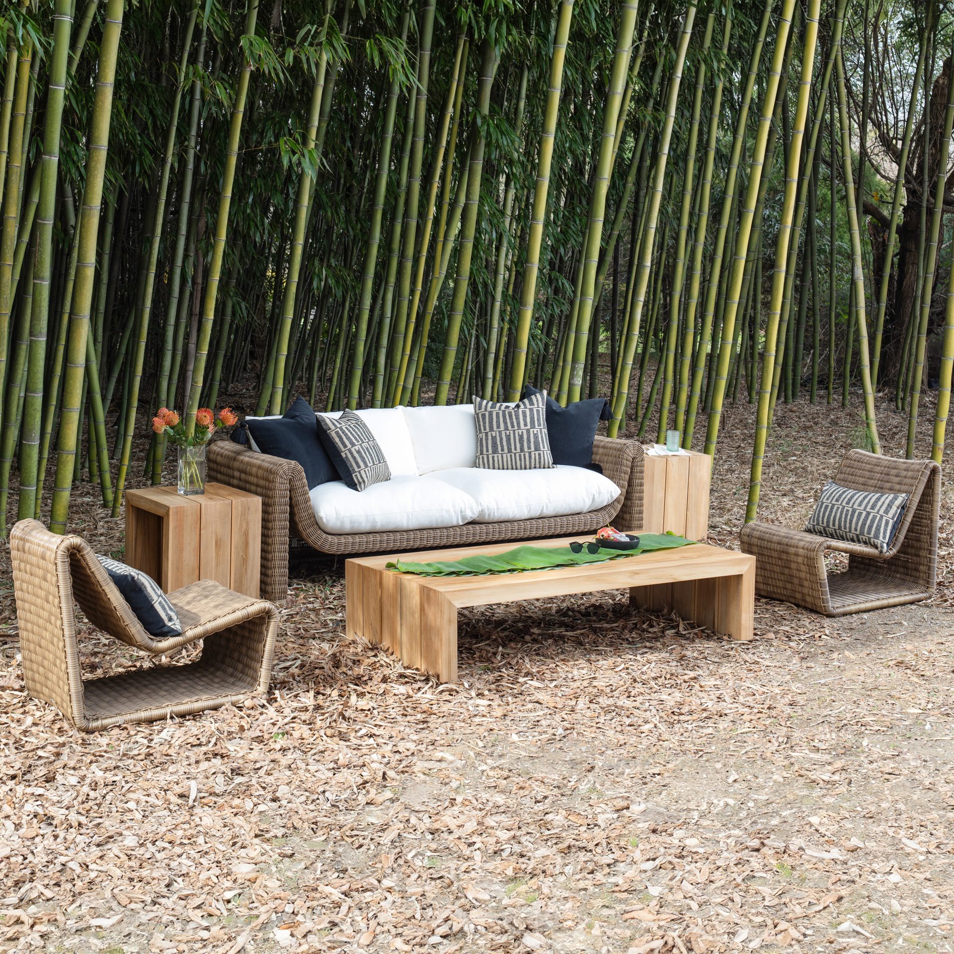 Outdoor wicker patio furniture set among bamboo grove.