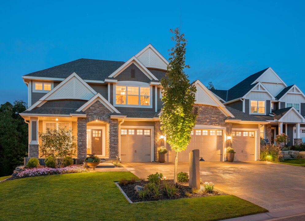 Modern suburban house at dusk with lights on.