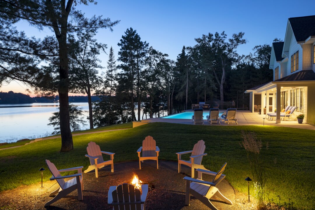 Lakeside patio with fire pit and sunset view.