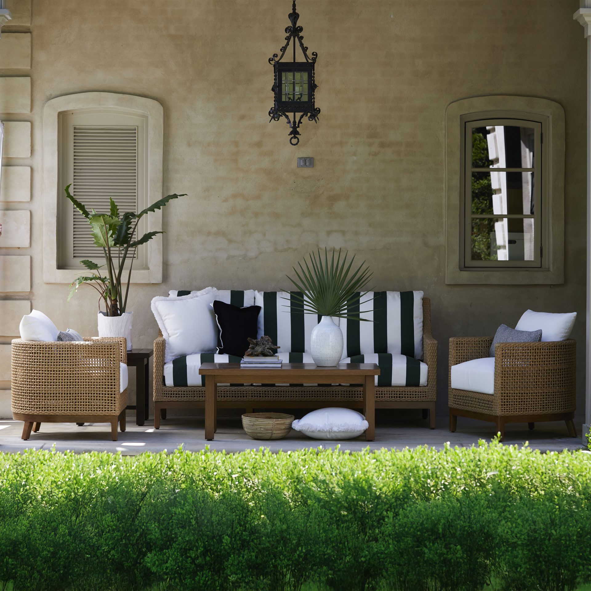 Stylish outdoor patio with wicker furniture and plants.
