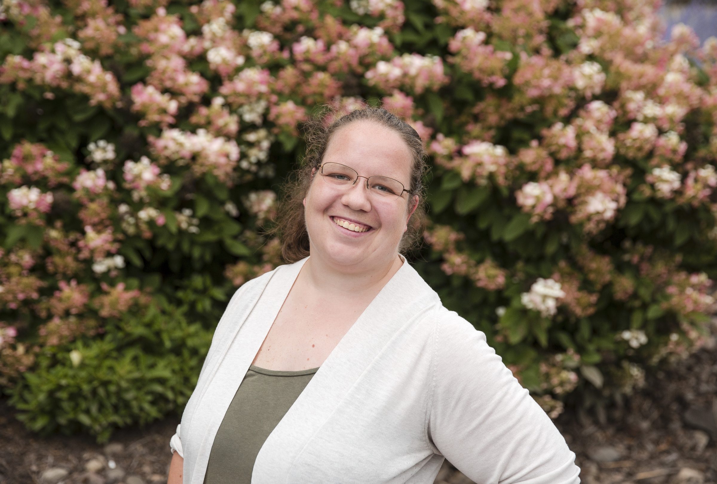 Smiling person in garden with blooming flowers.
