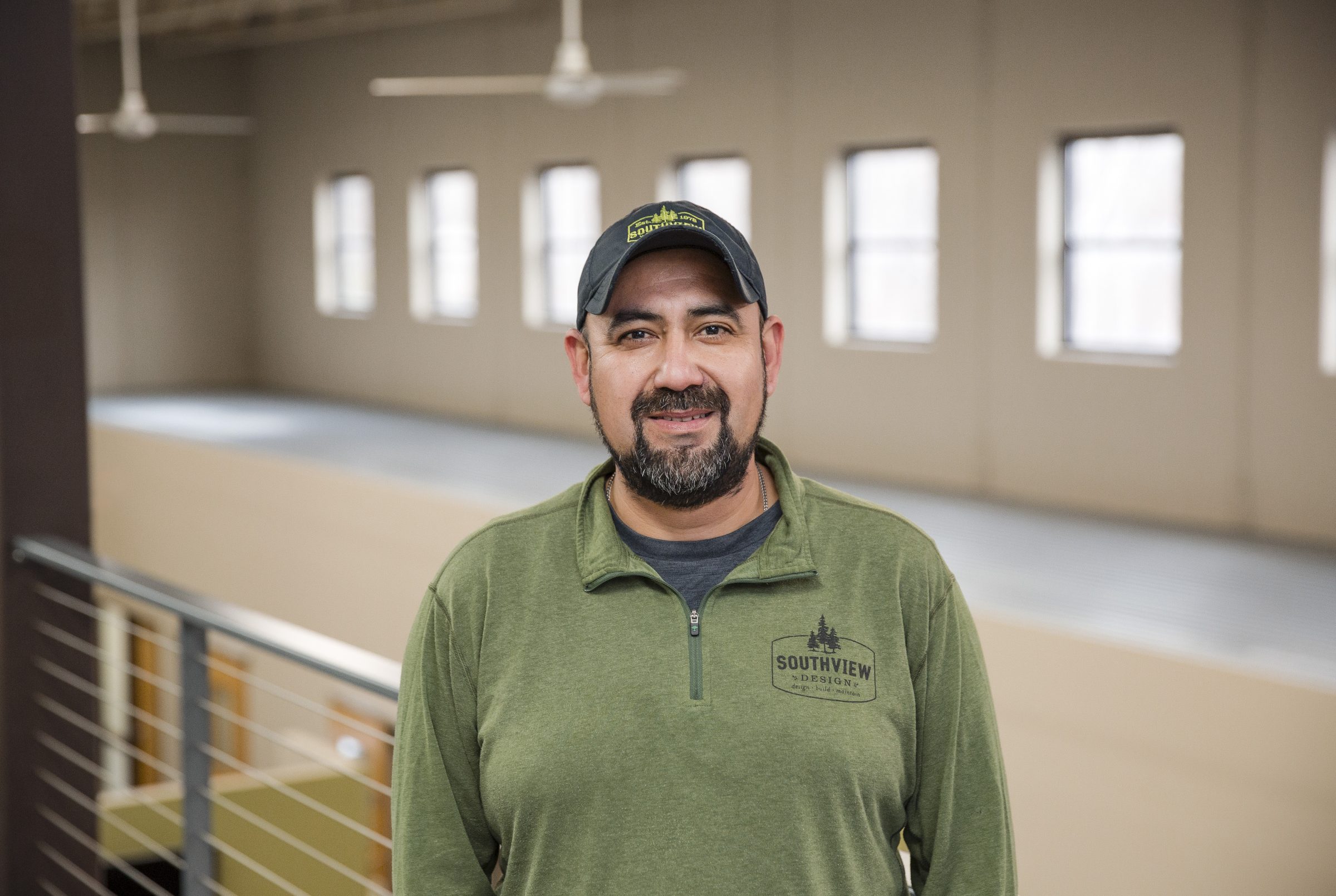 Smiling man in green shirt with cap indoors.