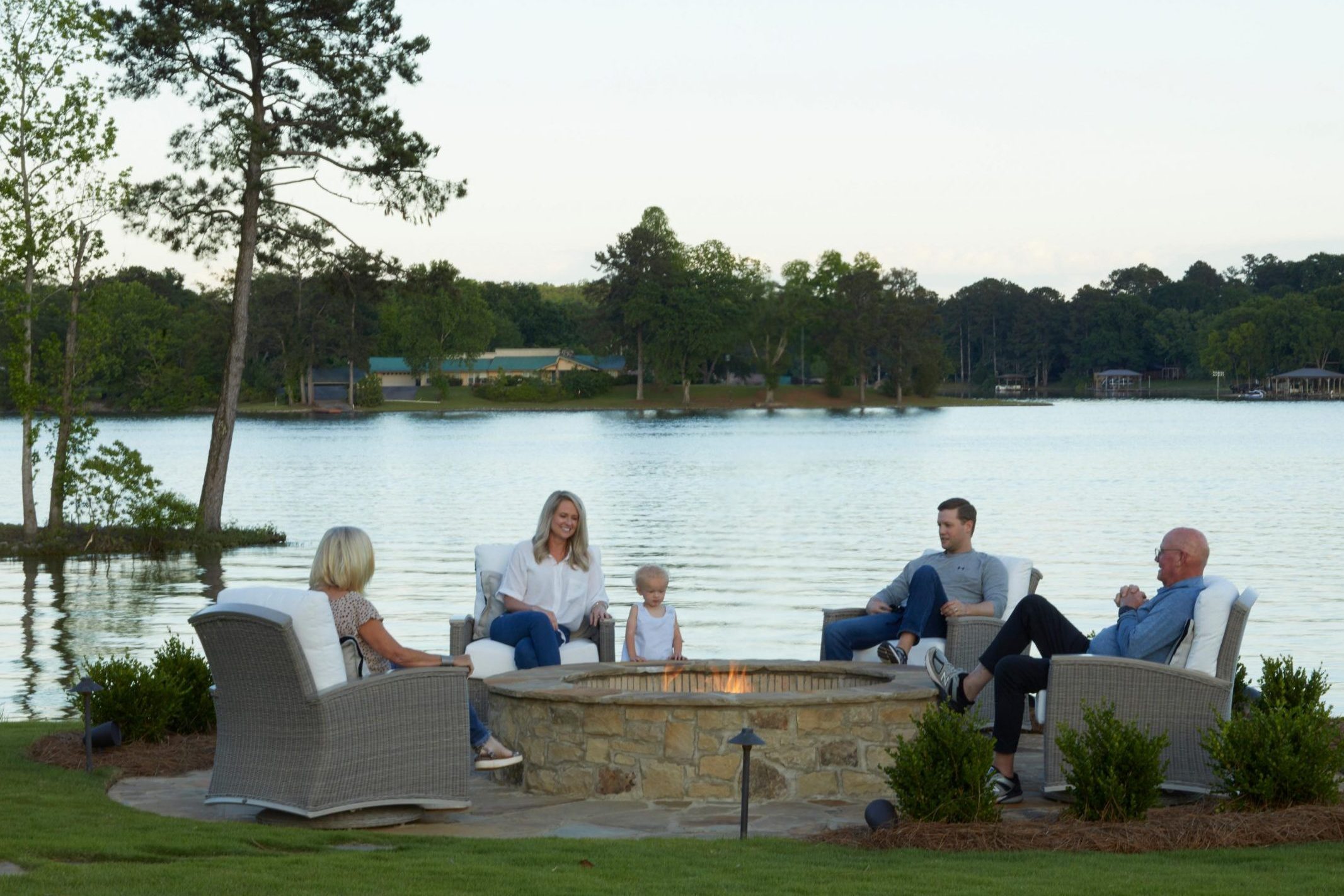 Family gathering around lakeside fire pit