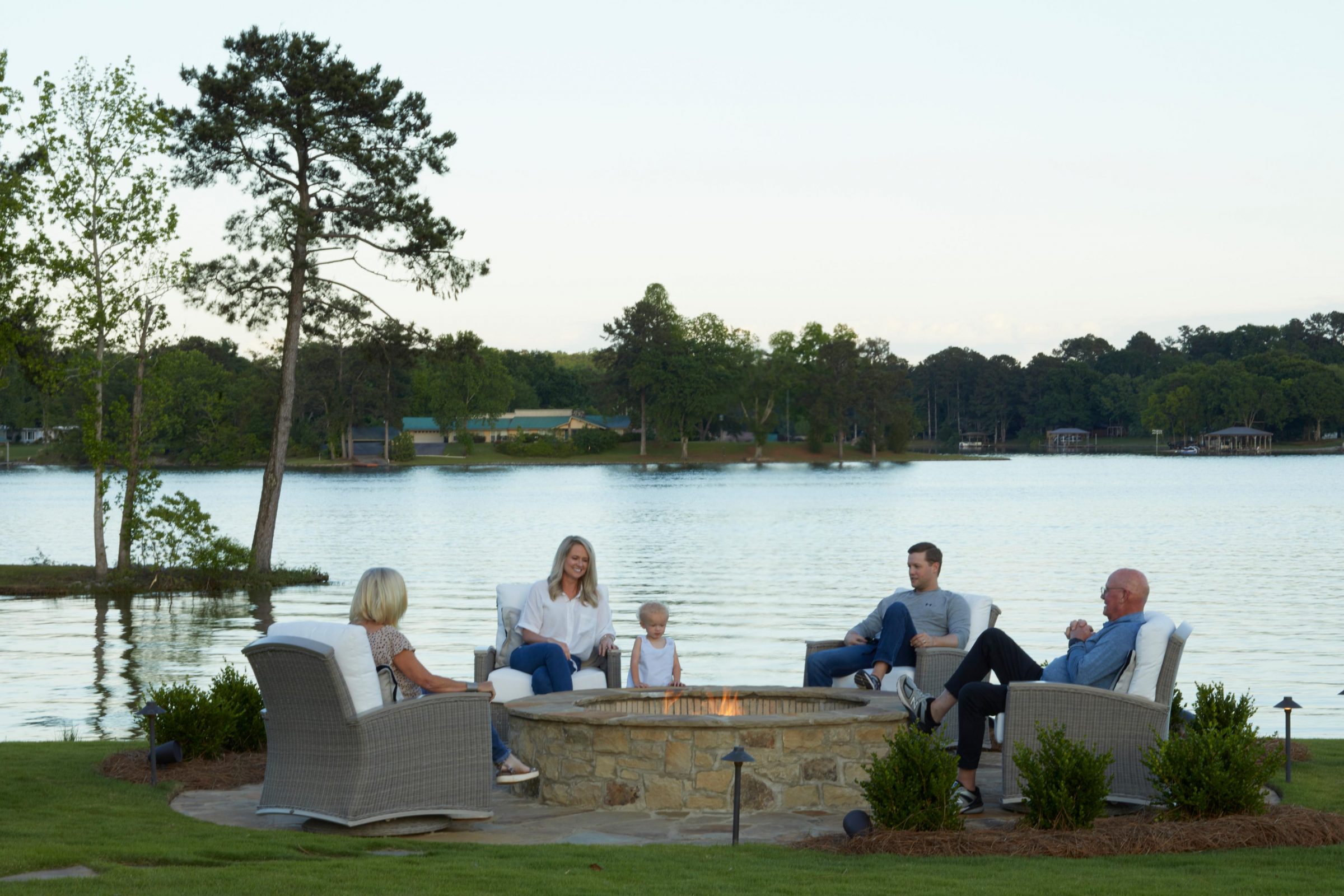 Family gathering around lakeside fire pit