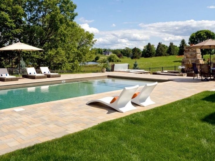 Backyard pool with lounge chairs and scenic view.
