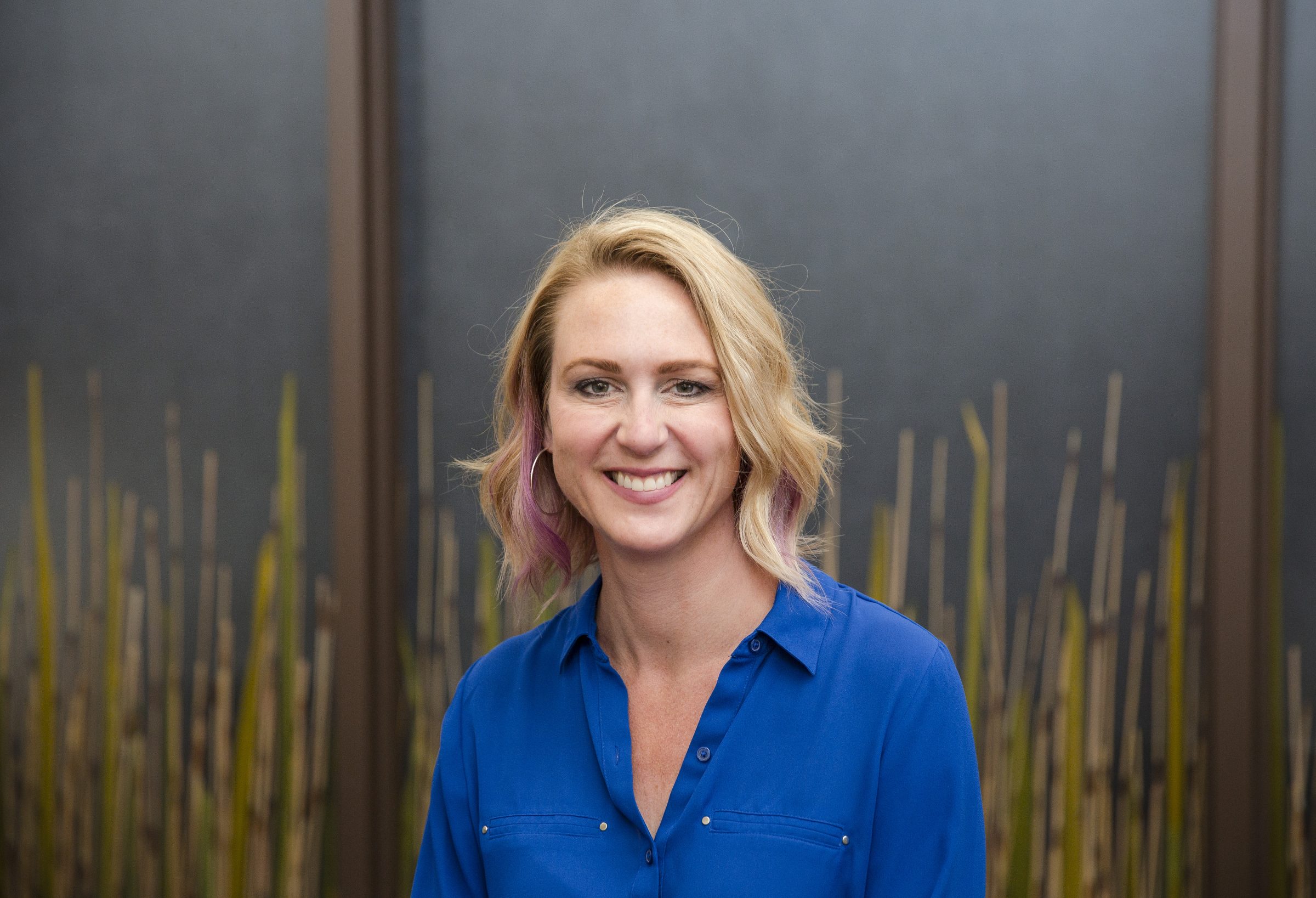Smiling person in blue shirt, indoor setting