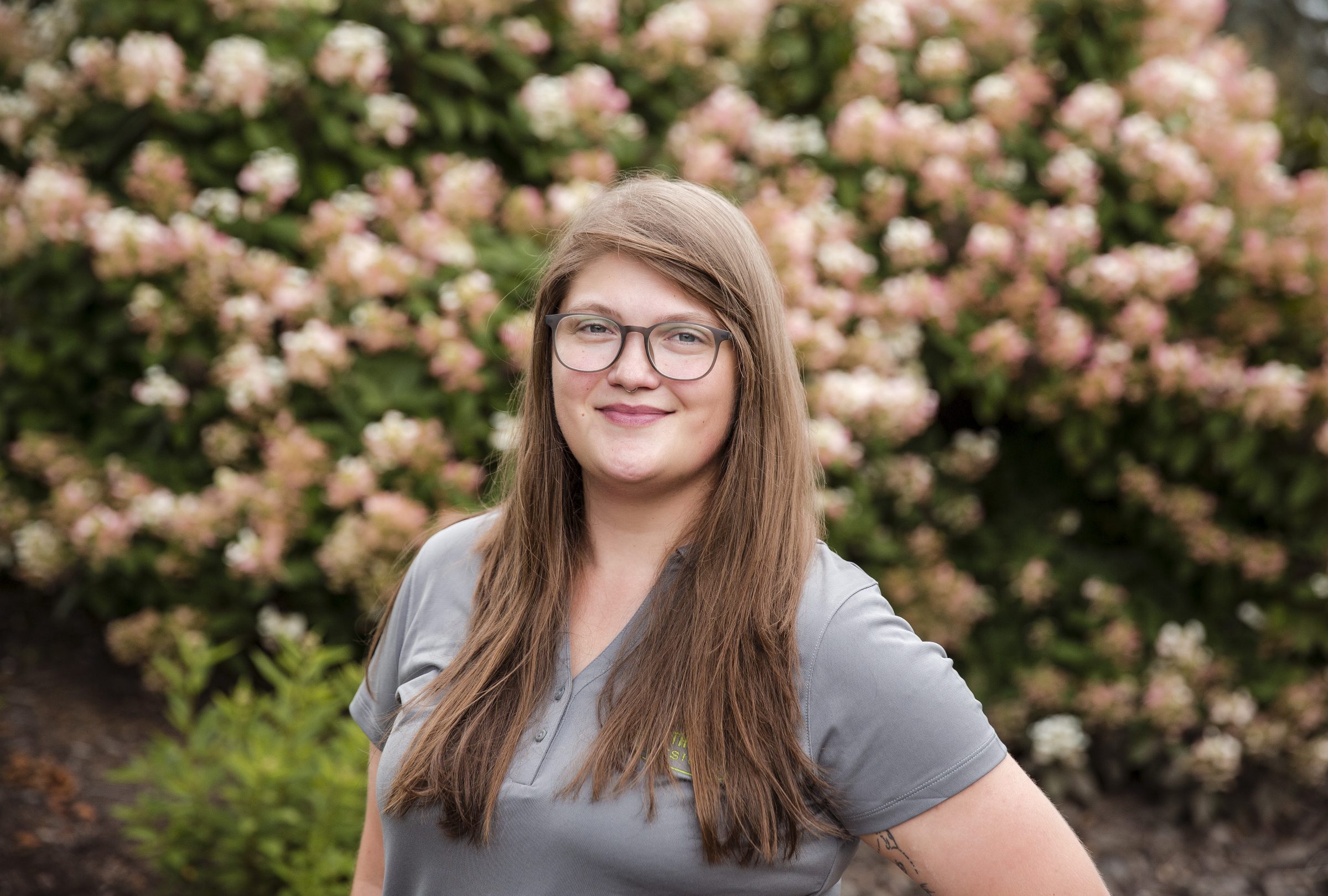 Smiling person in garden with blooming flowers.