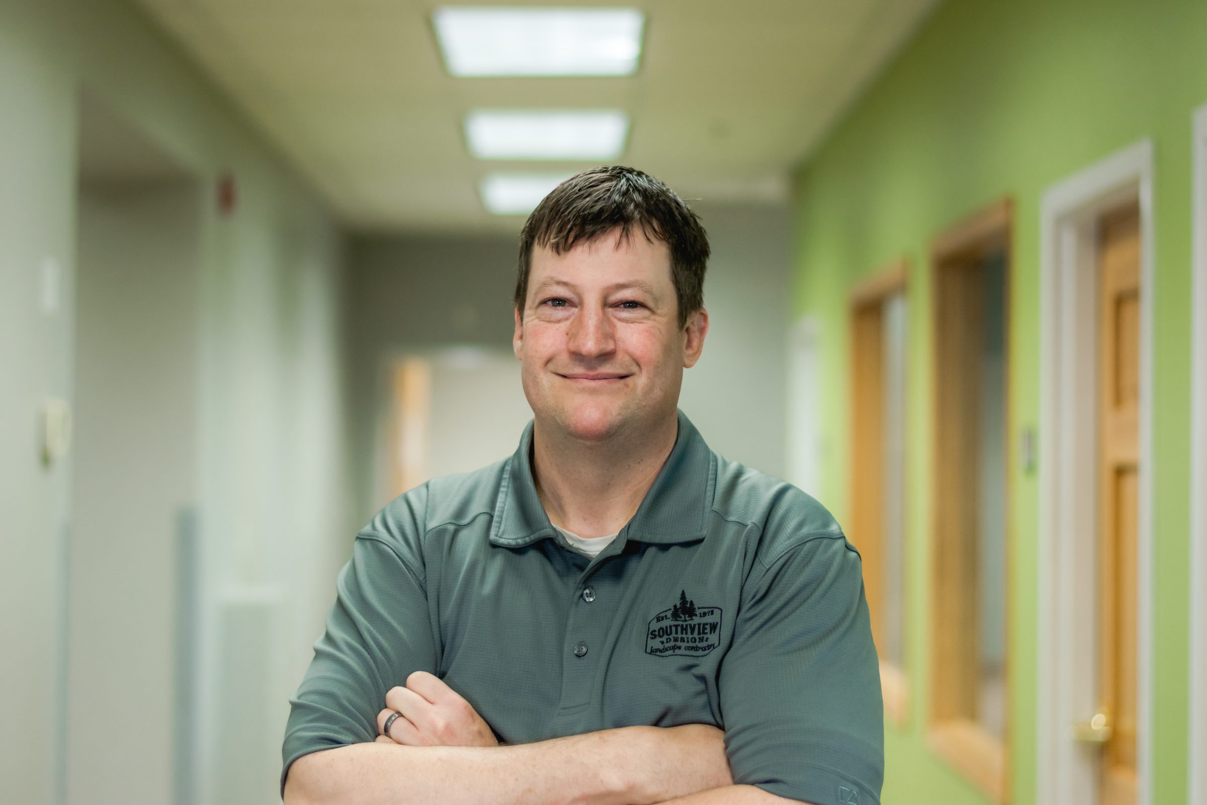 Smiling man in a green hallway.