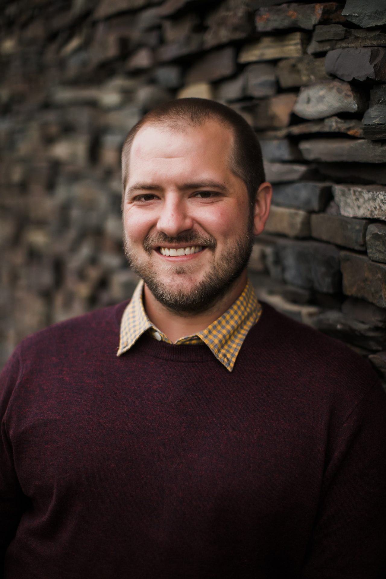 Smiling person in front of stone wall