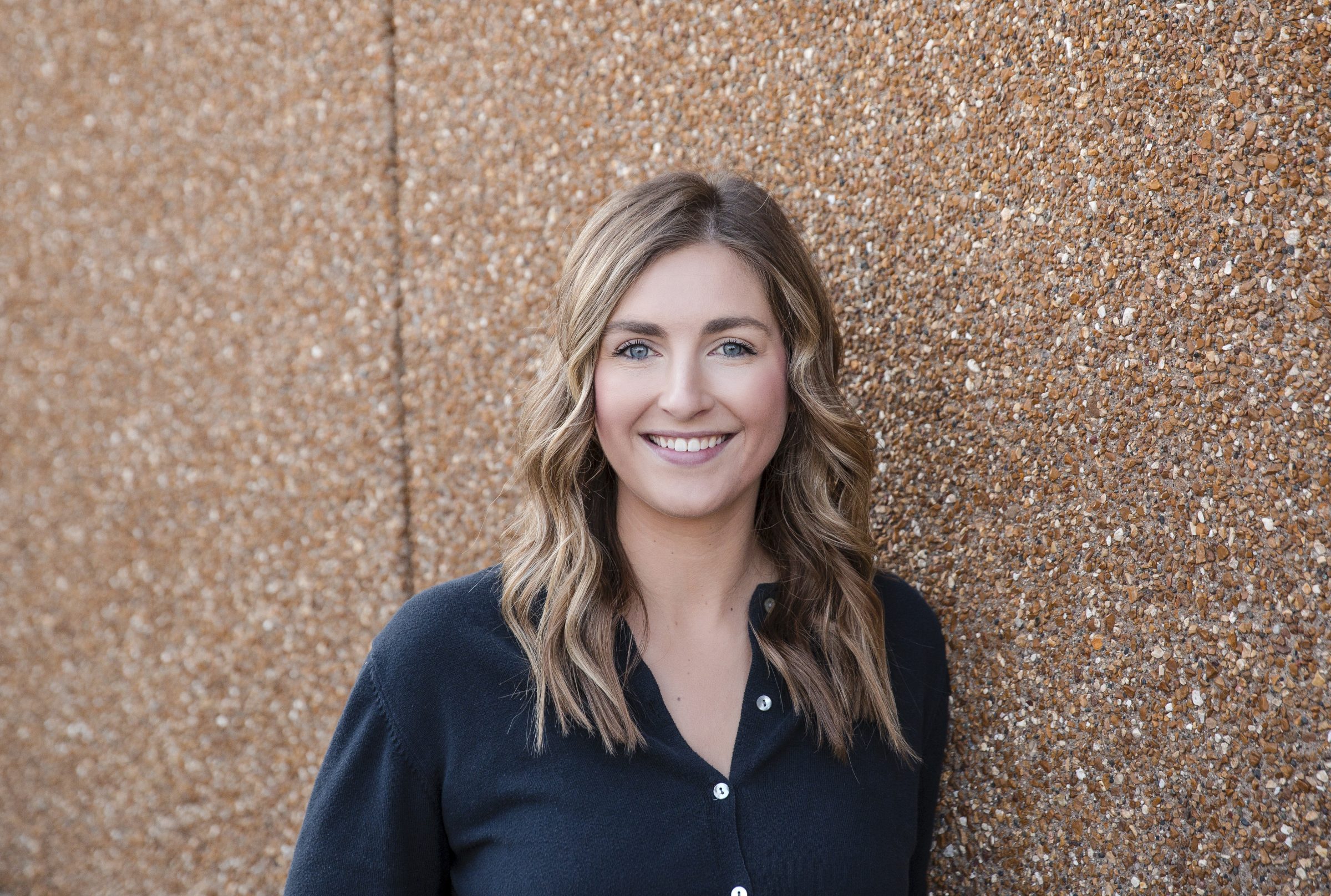 Smiling woman standing against textured wall