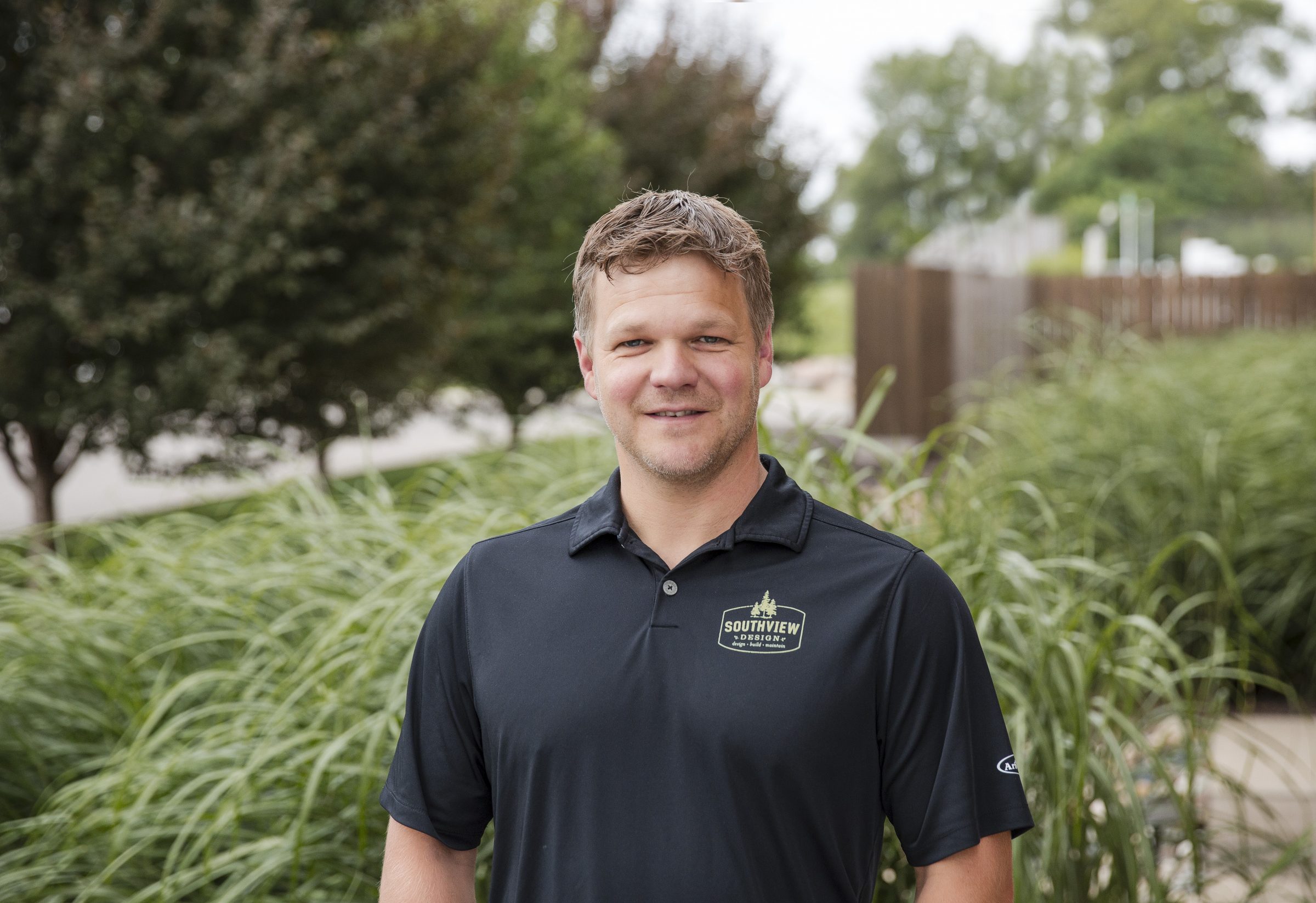 Smiling man outdoors in landscaped setting