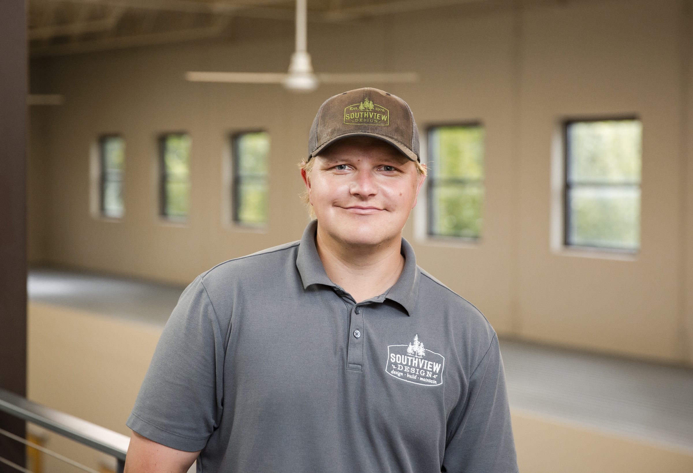 Person with cap and gray shirt smiling indoors.