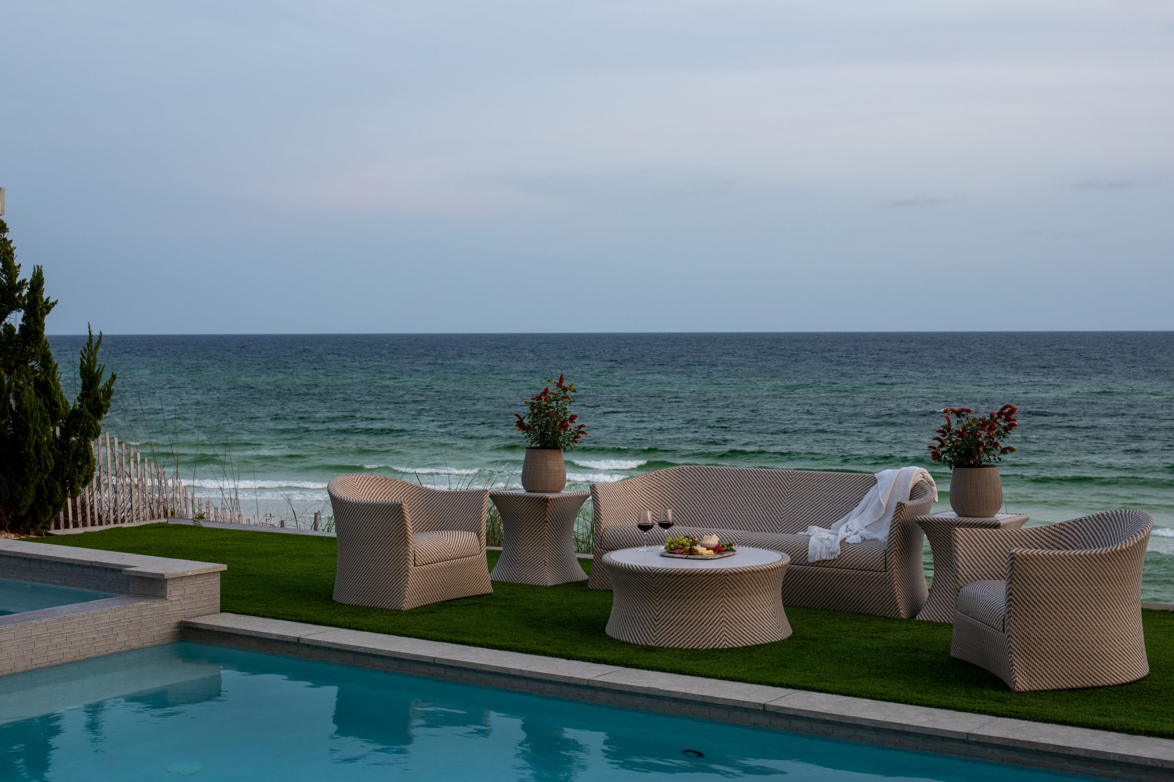Oceanfront patio with wicker furniture and pool.