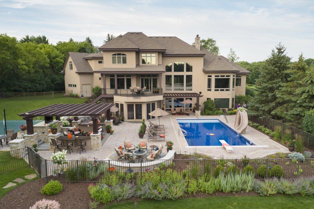 Aerial view of luxury backyard with pergola, outdoor kitchen, pool, and paver patio