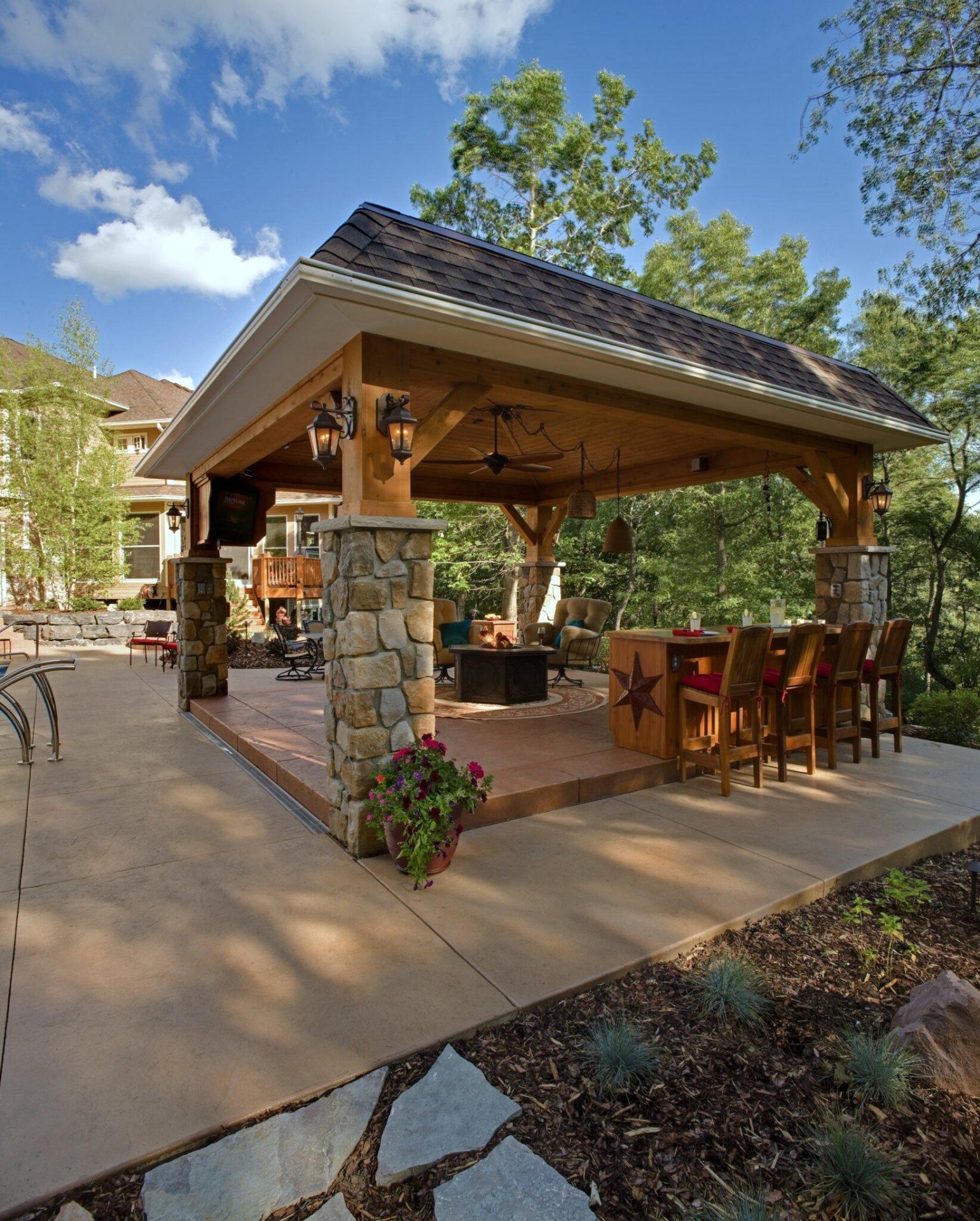 Covered stone column patio with wicker seating and open lawn views