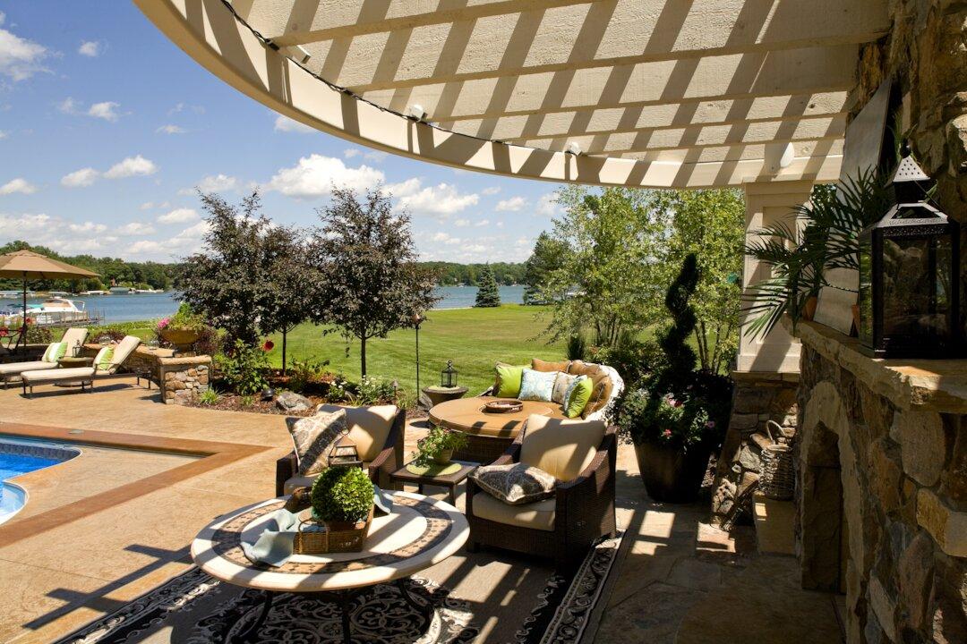 Curved pergola over lakeside patio with wicker seating and pool deck views