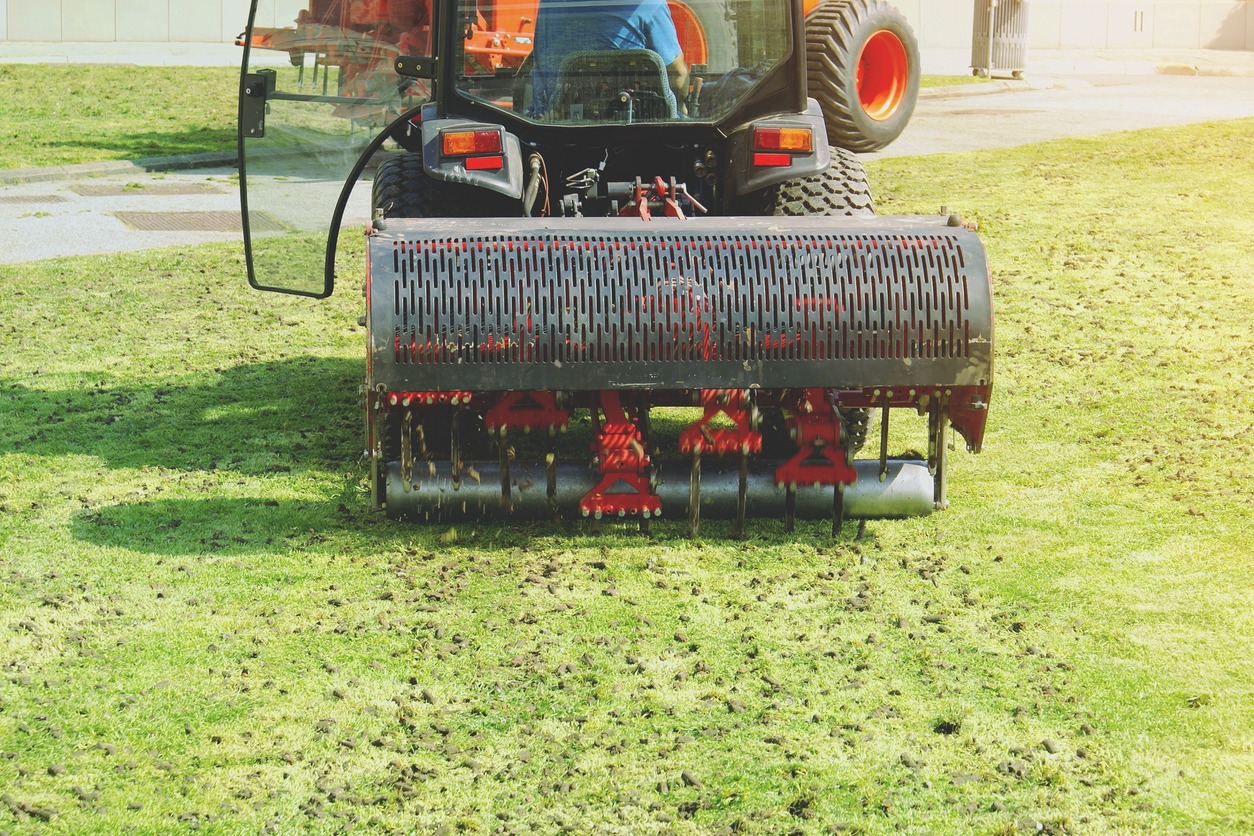 Lawn aerator machinery working on grass field.