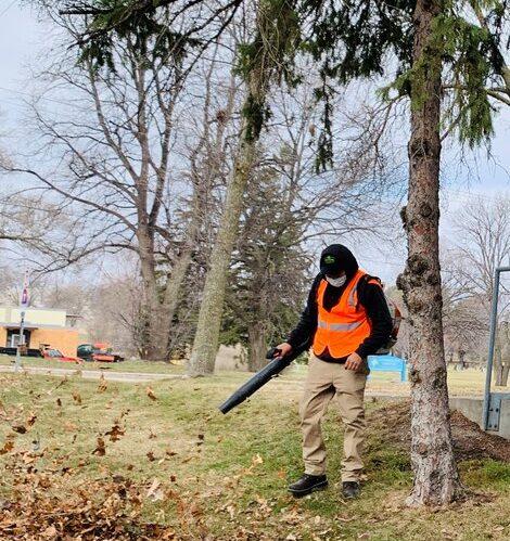 Landscape maintenance worker using a leaf blower for fall cleanup