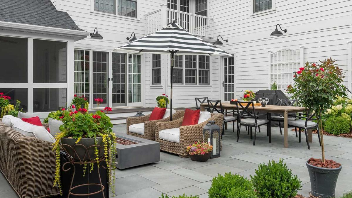 Large format paver patio with wicker seating, dining area, and garden beds