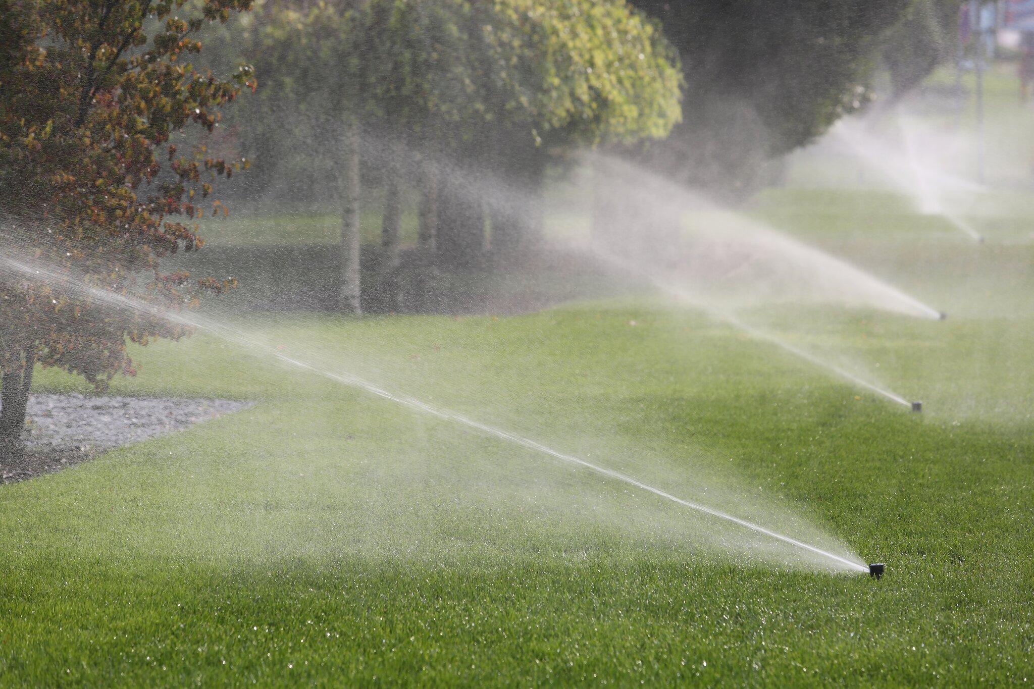Lawn irrigation sprinkler system watering a green residential lawn
