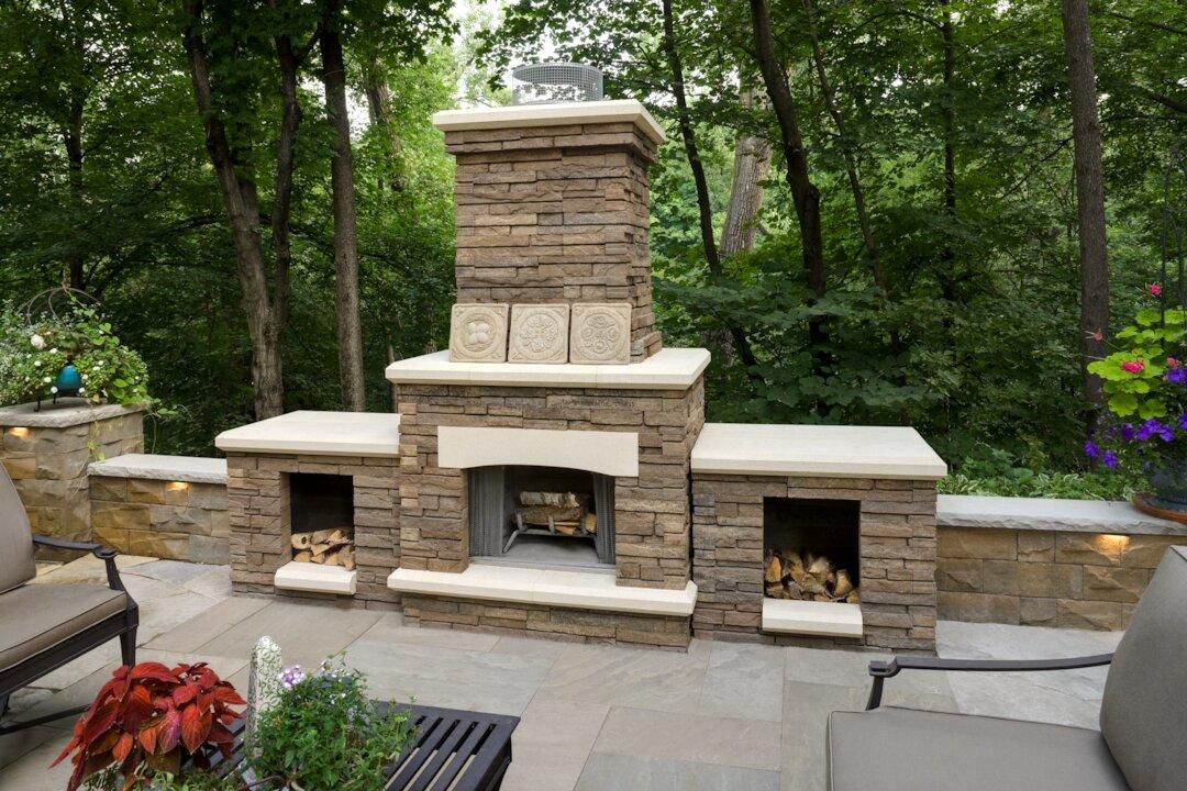 Stone outdoor fireplace with built-in wood storage and flagstone patio