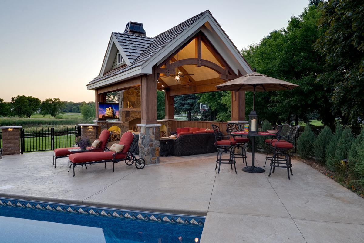 Timber frame pavilion with outdoor fireplace and TV beside a backyard pool
