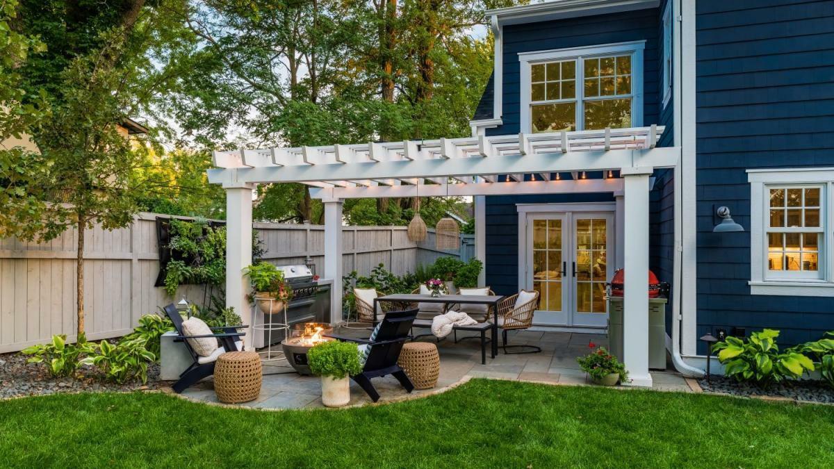 White pergola over backyard patio with fire pit and dining area at dusk