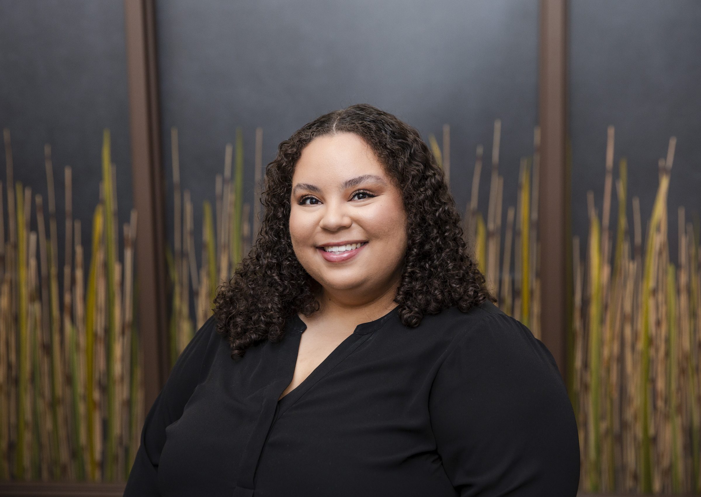 Smiling person with curly hair in a black shirt.