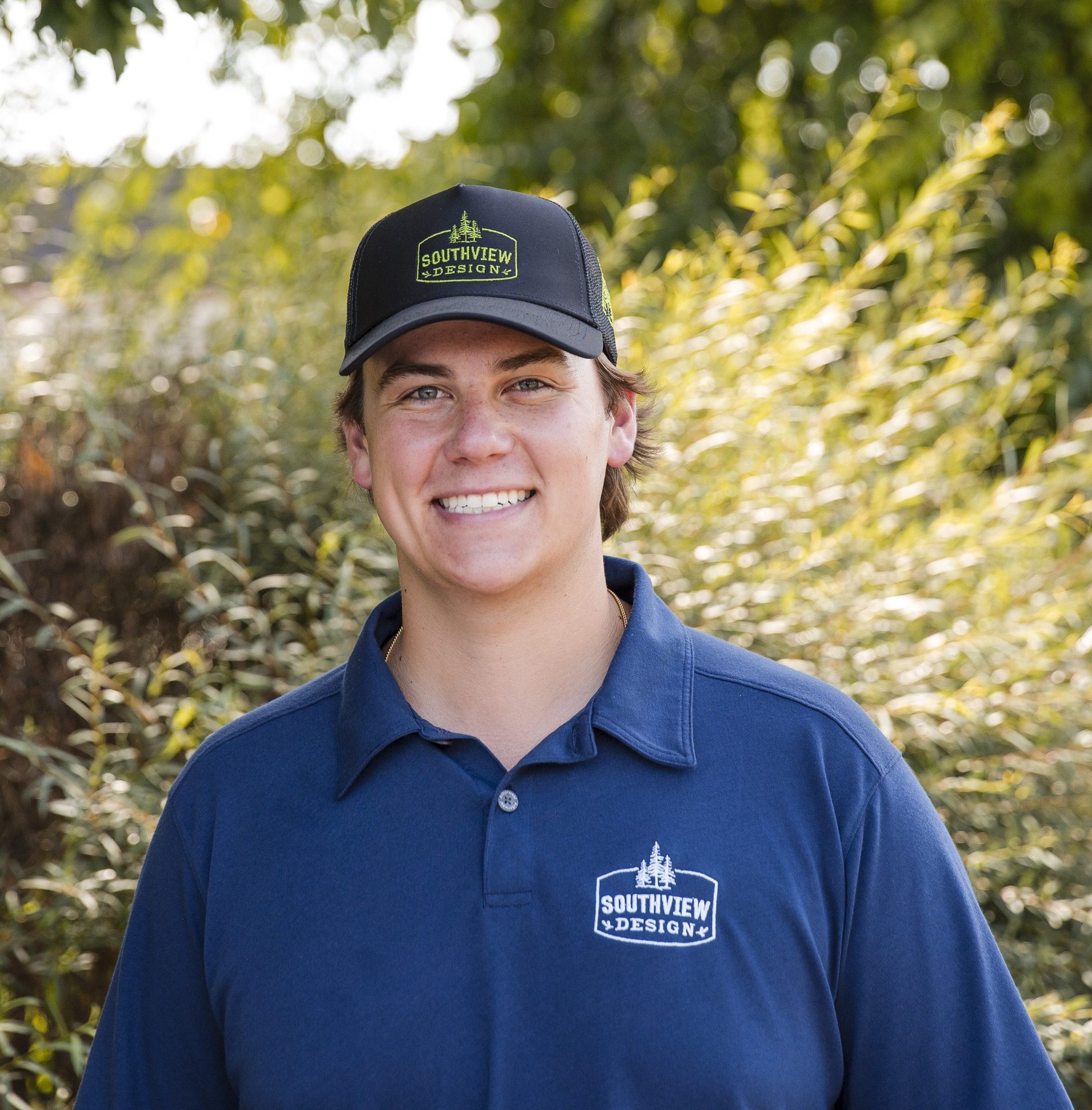 Person in blue Southview Design shirt smiling outdoors.