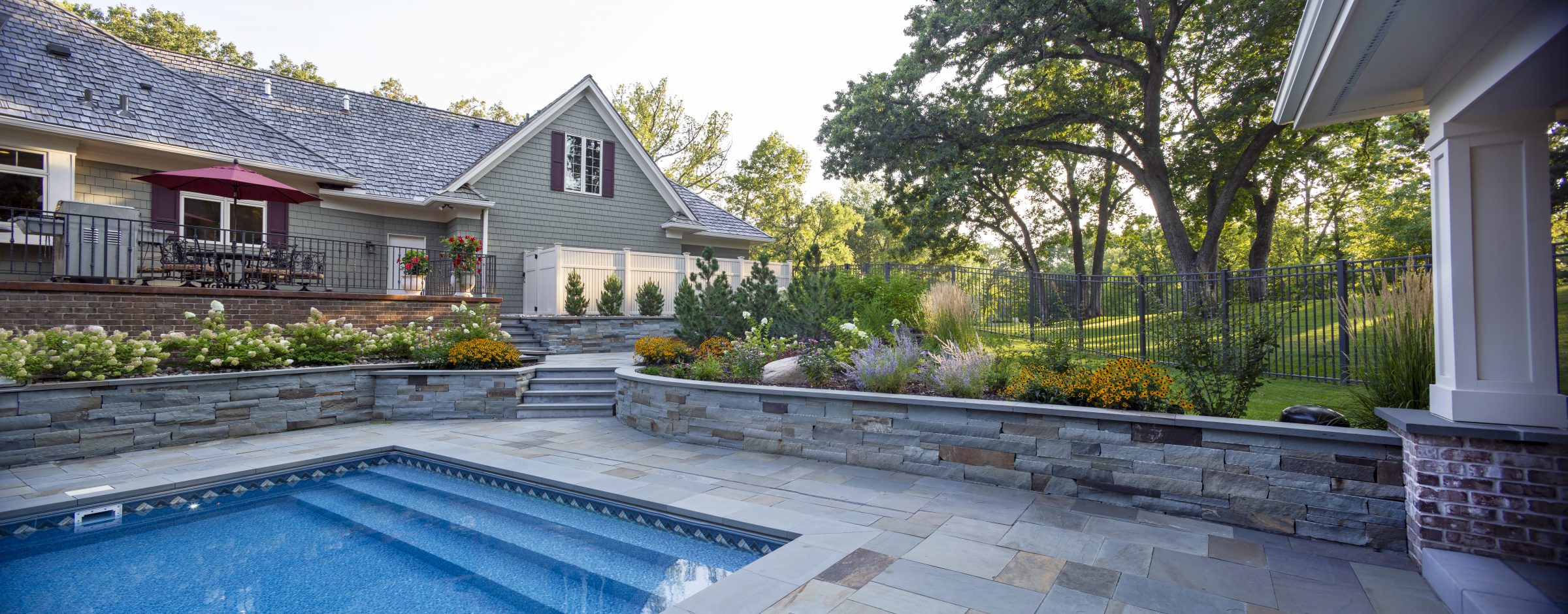 Backyard patio with pool and garden flowers.