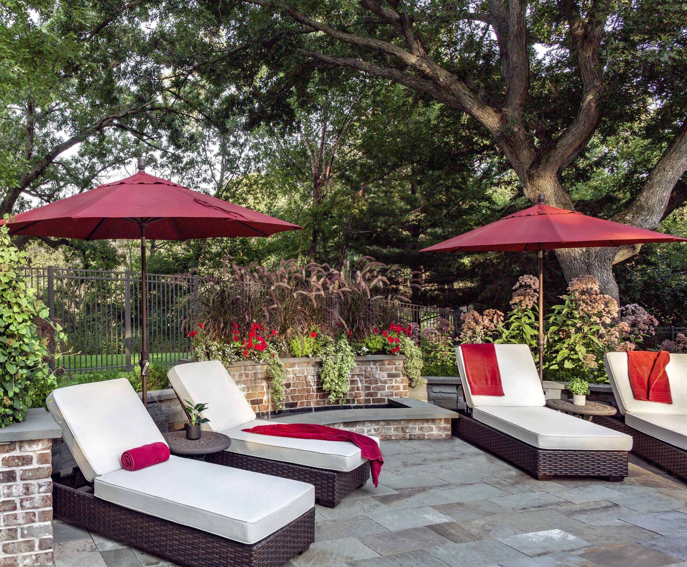 Elegant patio with loungers and red umbrellas.