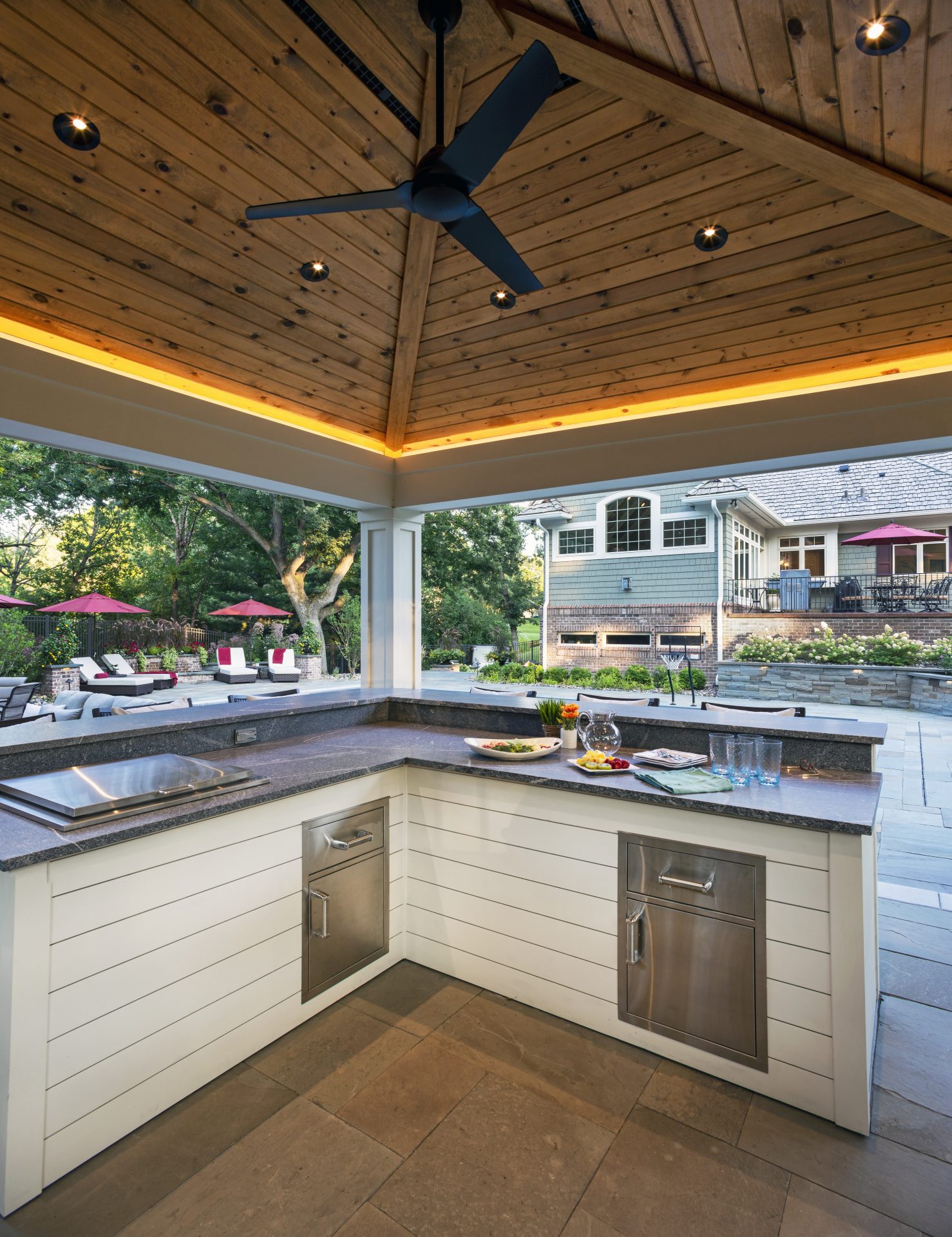 Outdoor kitchen with wooden ceiling and modern appliances.