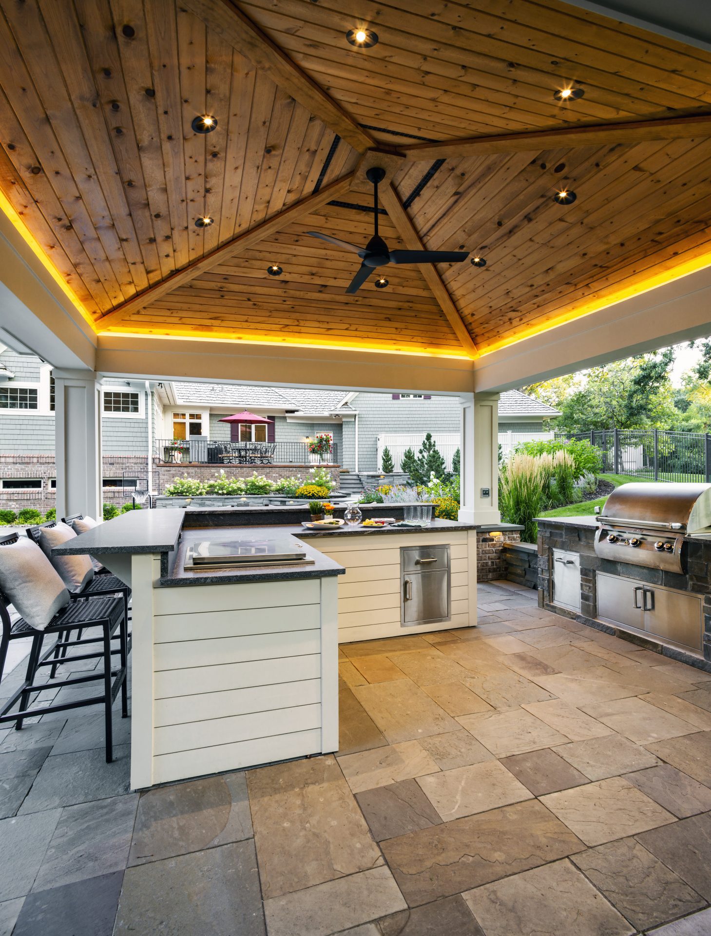 Modern outdoor kitchen with grilling area and seating.