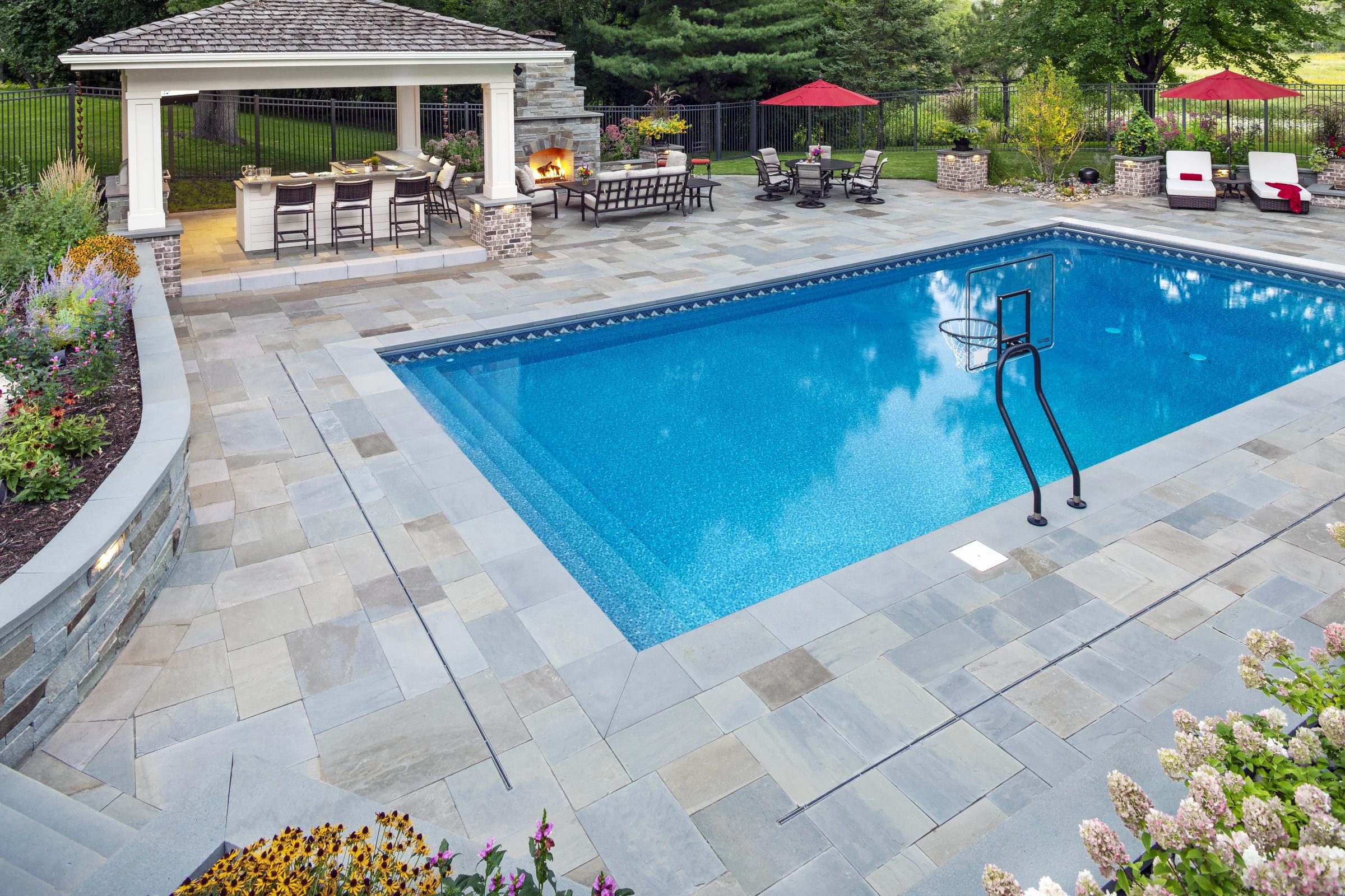 Luxury backyard pool with seating and fireplace.