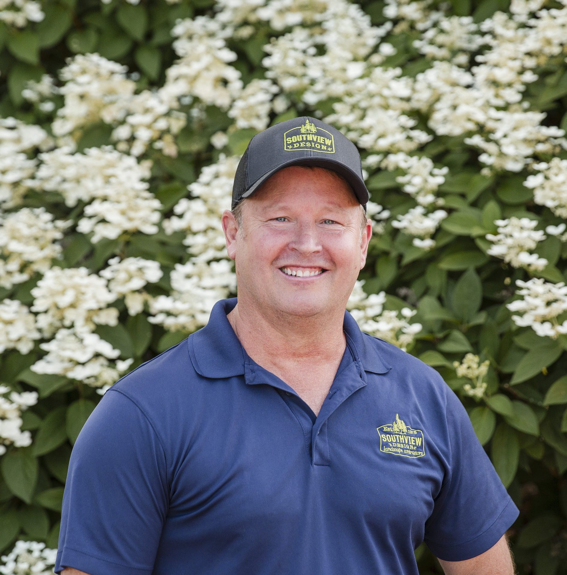 Smiling man in blue shirt and cap with flowers
