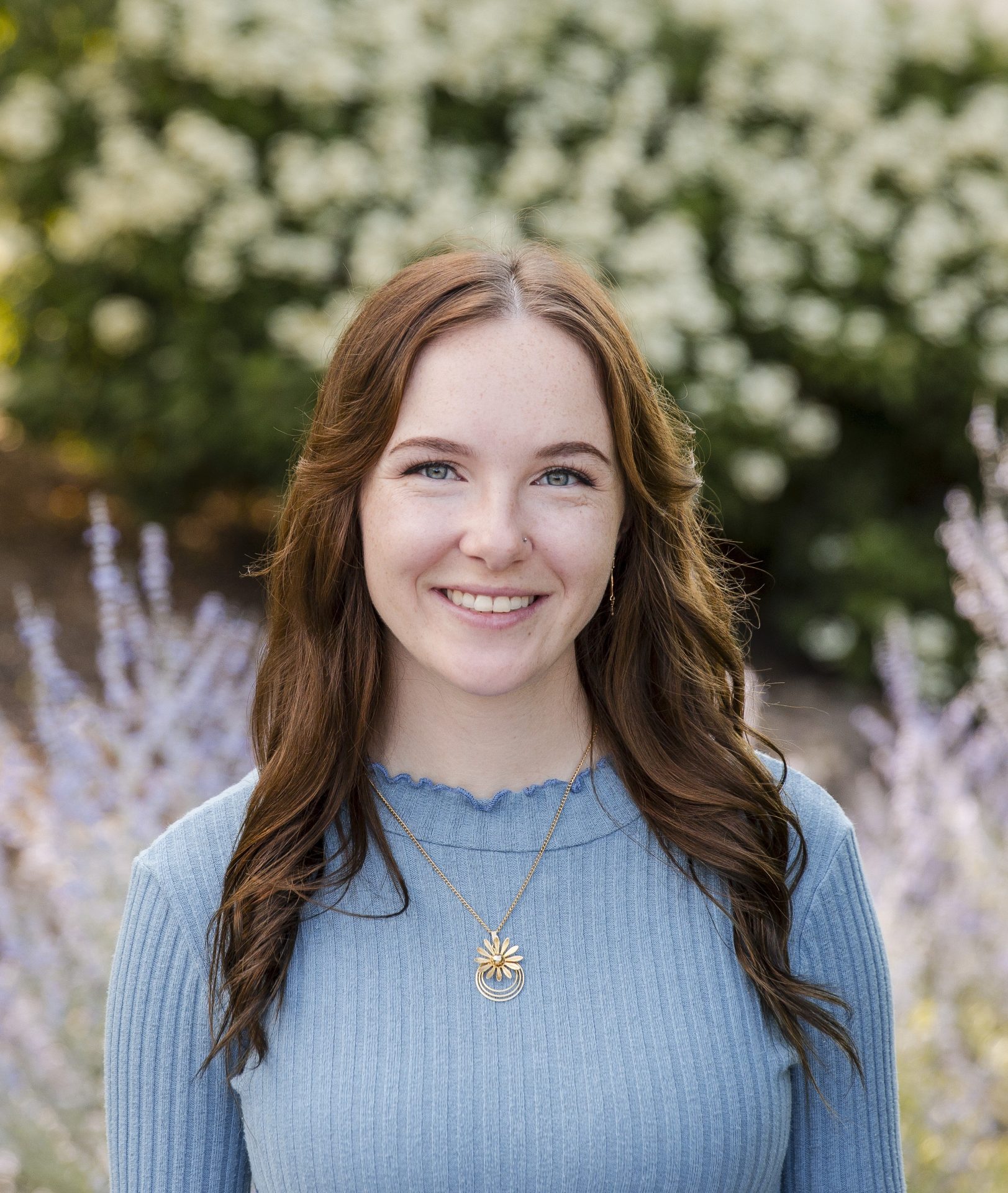 Smiling woman in garden with floral background.