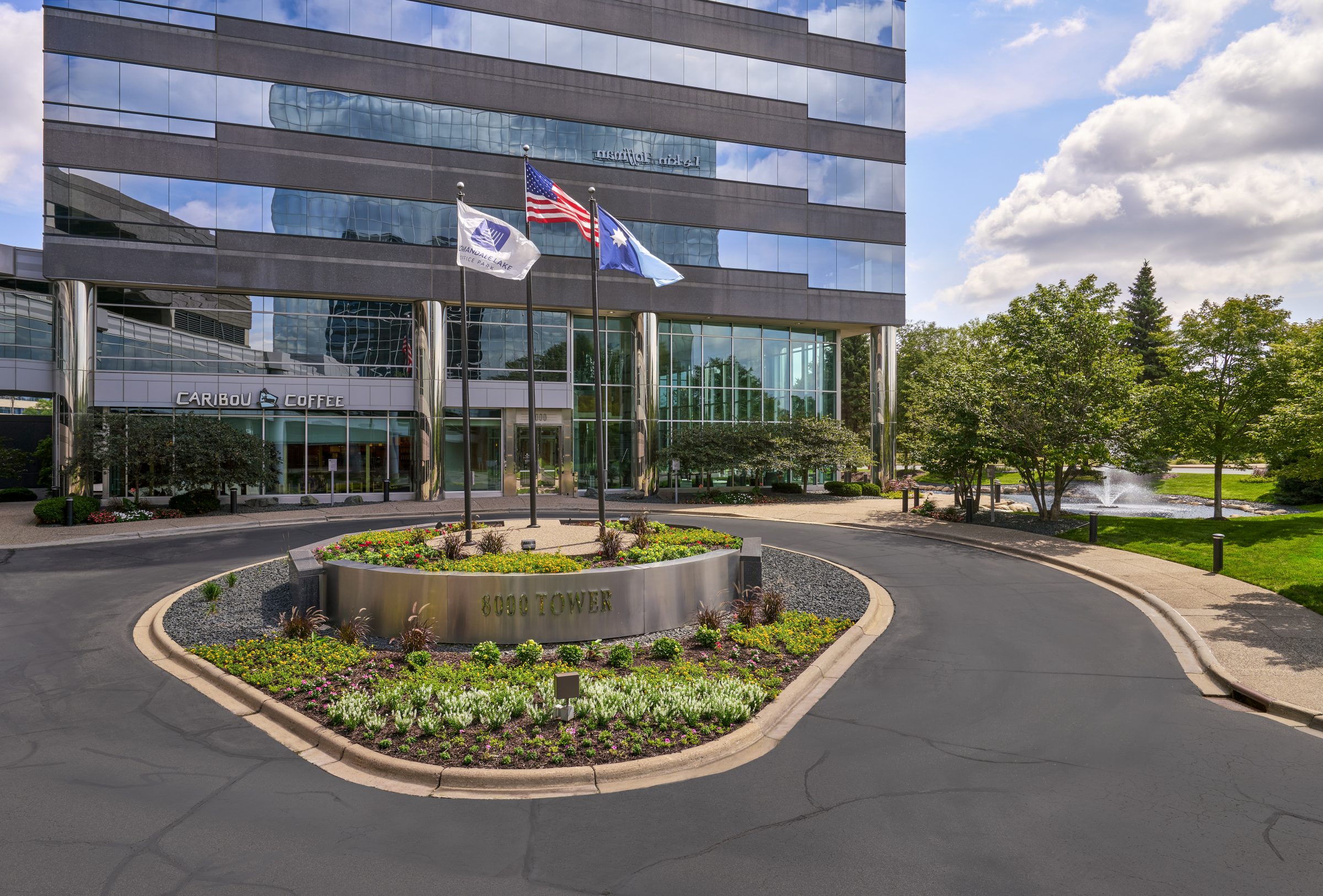 Building entrance with flagpoles and circular planting island at Normandale Lakes Office Park