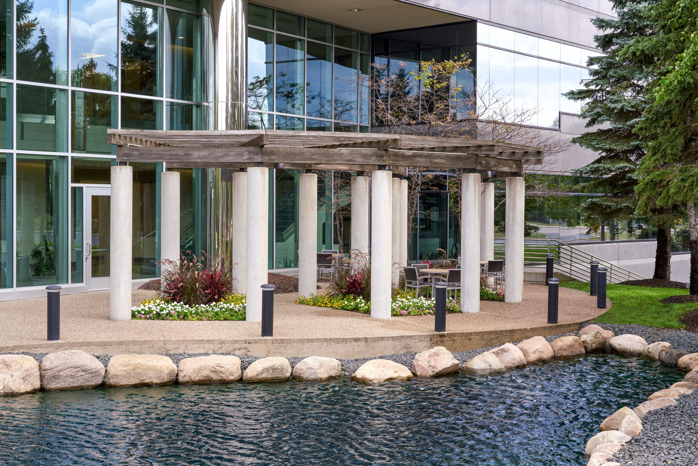 Modern office building with pond and seating area.