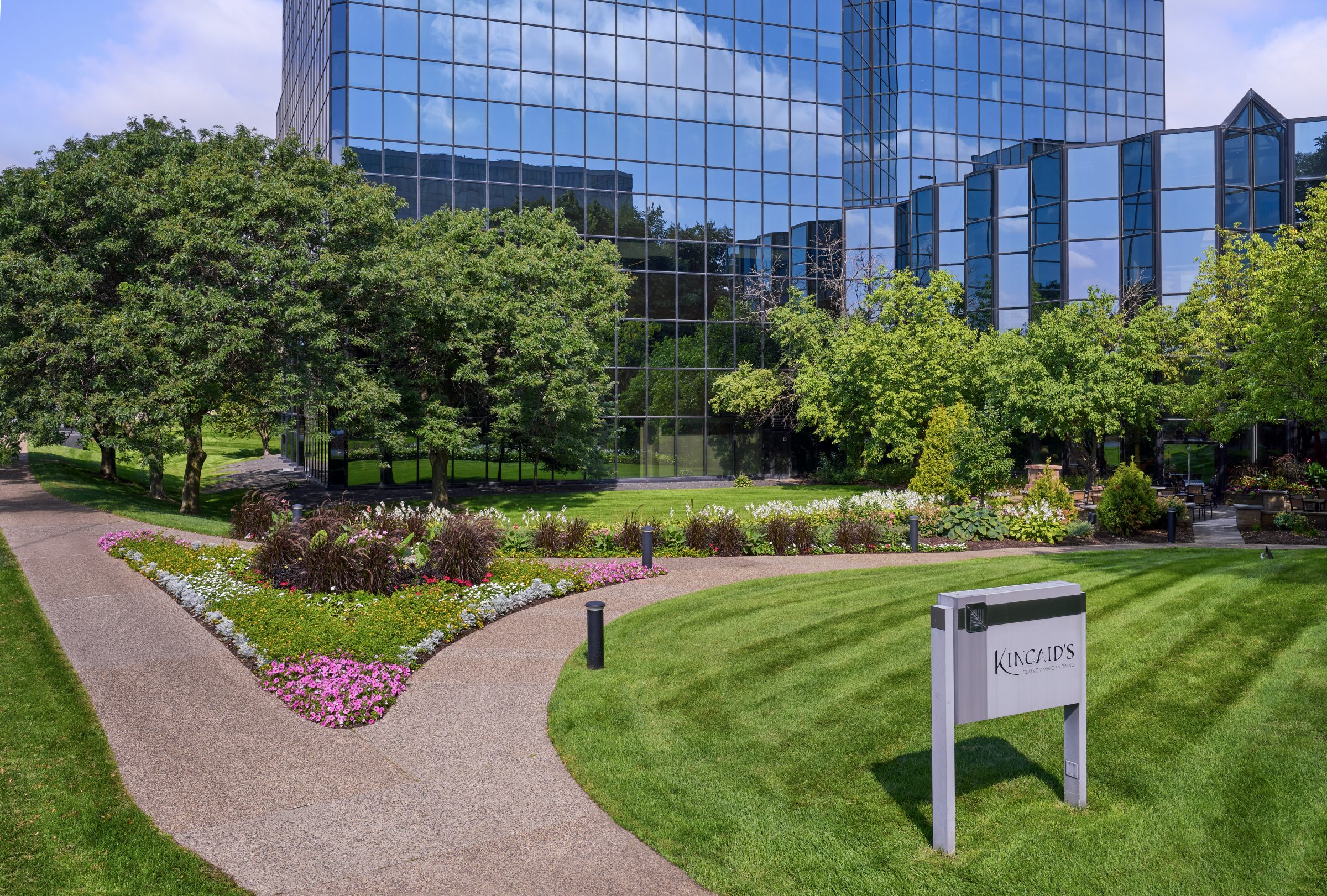 Landscaped walkway and planting bed in front of a glass office building at Normandale Lakes Office Park
