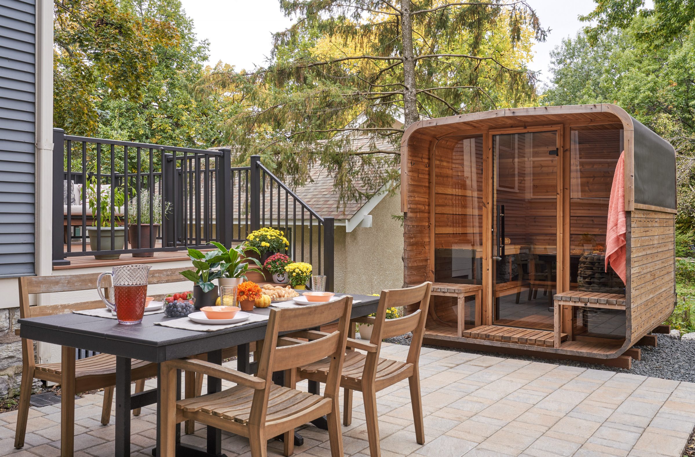Outdoor dining area with wooden sauna and trees.