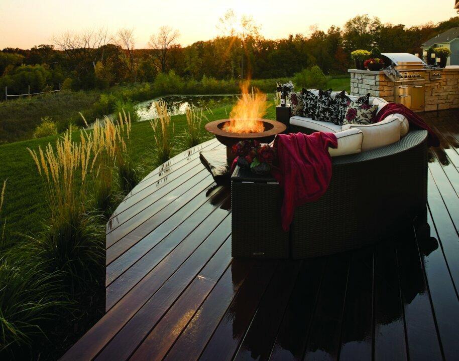 Gas fire bowl and outdoor lounge seating on a backyard deck styled for fall.
